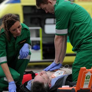 Two paramedics use an AED on an unconcious male
